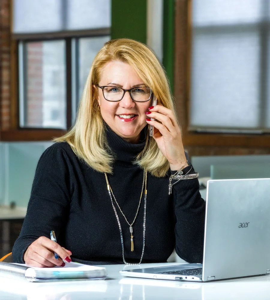 A woman talking on her phone while seated beside a laptop